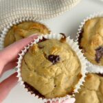 A hand holding a peanut butter banana muffin