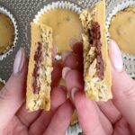 Hands holding two halves of a pb&j oat cup