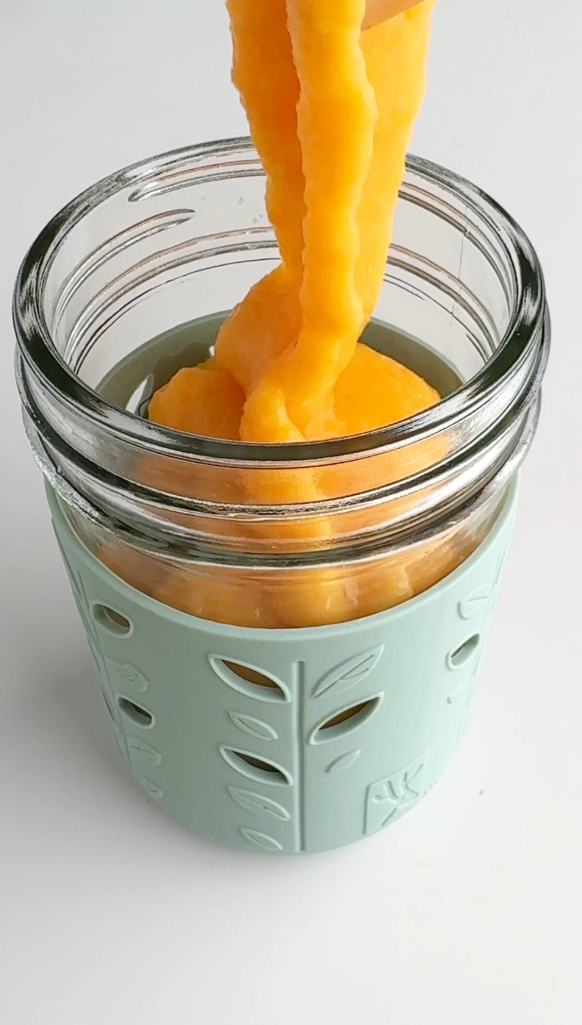 Carrot smoothie being poured into a cup