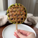 A spinach waffle pop with peanut butter and sprinkles on top.