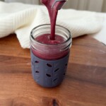 Pouring a blueberry citrus smoothie into a cup